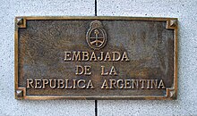 Placa de metal con letras y el escudo grabados para indicar el edificio de la embajada de la República Argentina en la ciudad de Madrid.