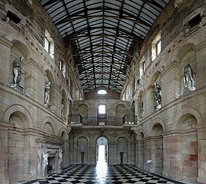 The inside of the central block's main entrance. The fire-damaged stucco statues at first-floor level are permanently affixed to the walls; the missing ceiling was destroyed in the fire of 1822. The roof is modern. Seaton Delaval Hall central block inside.jpg