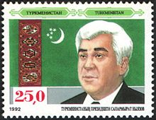 Portrait d'un homme aux cheveux blancs devant le drapeau du Turkménistan. En haut, le nom Turkmenistan écrit en cyrillique et alphabet latin. En bas à gauche, le chiffre 25,0 en rouge ; un peu plus bas en petit, la date 1992.