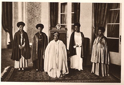 Empress Menen Asfaw seated in the center and Standing women from left to right are Princess Tsehai, Princess Tenagnework, and Princess Zenebework, her daughters, and on the far right is Princess Wolete Israel Seyoum, her daughter-in-law.