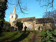 A low angle looking upwards of a small church framed through trees