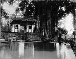 Badplaats Kedjawar met het badhuis onder de waringinboom in de buurt van Kalibagor en Poerwokerto. Boven het dak beschermt een raamwerk van bamboe de dakbedekking tegen vallende bladeren (1900).