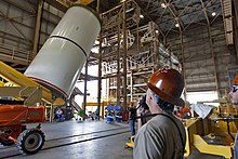 Technicians practice crane operations with an inert booster rocket segment inside the RPSF.