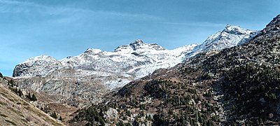 Photographie avec au centre une pointe enneigée avec de la végétation au-dessous où la neige est moins présente.