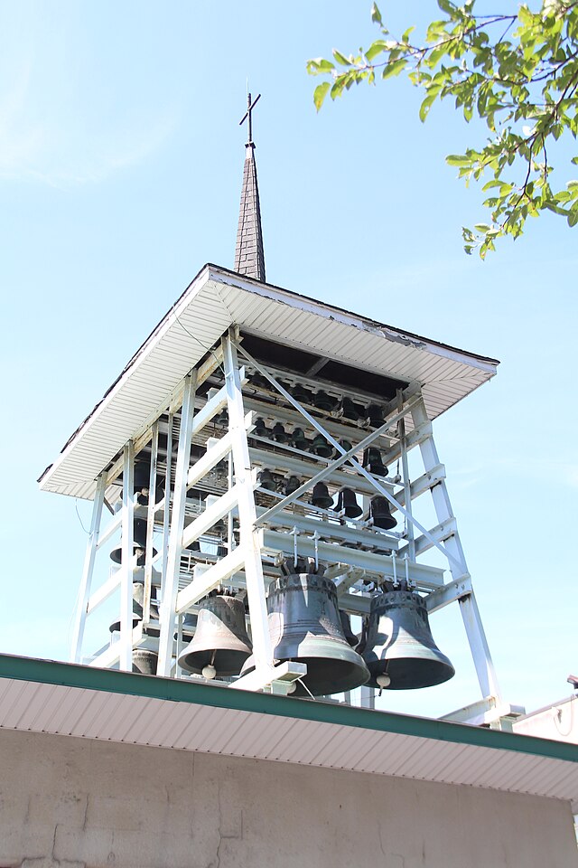 A steel structure containing 56 hanging bells of various sizes and topped with a roof spire and a cross