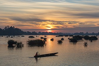 Silhouette d'un pêcheur sur sa pirogue au lever du soleil, à Don Det. Janvier 2019.