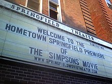 A board reads "Welcome to the Hometown Springfield Premiere of The Simpsons Movie