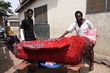 A modern fantasy coffin in the shape of a red rooster, Ghana Ataa Oko and Kudjo Affutu with Oko's red coq coffin 2009. Foto Regula Tschumi.JPG