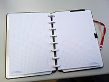 Caderno Inteligente aberto com discos brancos e folhas quadriculadas