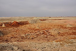 Lansekap di sekitar sumber air panas di Dallol; bagian dari pemukiman yang ditinggalkan terlihat di cakrawala