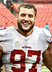 Nick Bosa in a 49ers jersey (with no helmet) smiling.