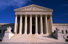 The gleaming white building of the United States Supreme Court, appearing like a Greek temple, stands out against a clear blue sky. Above the pillars is inscribed "EQUAL JUSTICE UNDER LAW".