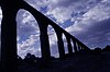 Vue panoramique de l'aqueduc de Padre Tembleque ; la photographie est à contre-jour et les arches apparaissent en noir contre le ciel.