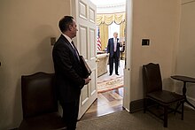 Chief of Staff Reince Priebus looks into the Oval Office as President Donald Trump reads over his notes. Chief of Staff Reince Priebus looks into the Oval Office as President Donald Trump reads over his notes, March 2017.jpg