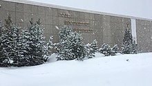 A one-storey stone building with École Secondaire Népisiguit written on the front during a snowstorm.
