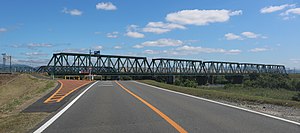 東海道本線の揖斐川橋梁と揖斐川の右岸を通る岐阜県道261号脛永万石線、大垣市新開町にて（2017年（平成29年）5月28日撮影）