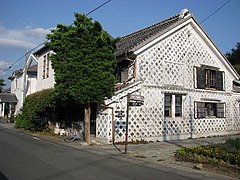 Maison dont un pan entier est recouvert de tuiles dans un style namako à Matsuzaki.