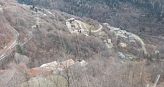 Photographie de plusieurs villages, avec plusieurs maisons installées dans le flanc de la montagne entre la forêt de feuillus sans feuille.