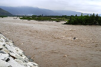 Photographie d'un fleuve en crue dans une région montagneuse.