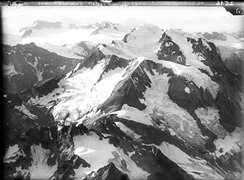 Blick nach Norden: Der scharfe schneefreie Grat in der Mitte führt hoch zum schneebedeckten Gipfel des Piz Urlaun, links davon das grosse Schneefeld des Gliemsgletschers. Die erste Maschine prallte von links in den Berg (Walter Mittelholzer, 1919)