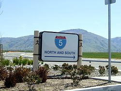 Highway directional sign in Wheeler Ridge, with Tehachapi Mountains beyond