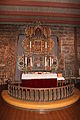Altaret er i den tidligere tømmerkyrkja, som har rosemåling på veggene.