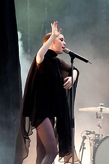 A dark blonde woman (Lykke Li) performs on stage at an outdoors festival.