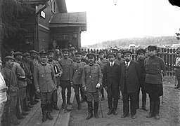 Photographie en noir et blanc à côté d'un bâtiment en bois d'hommes japonais et russes posant pour une photo officielle.