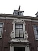 Statig patriciershuis met uit- en inspringende gevelpartijen, rechte kroonlijst; middenpartij met houten gebeeldhouwde versieringen, inwendig rechts en links van de middengang binnenplaatsen met houten betimmeringen met secreten. Fraaie stucwerken in de gang en deuren