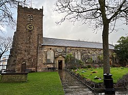 A stone church seen from the south-east with a square, battlemented tower to the left, and the body of the church extending to the right.