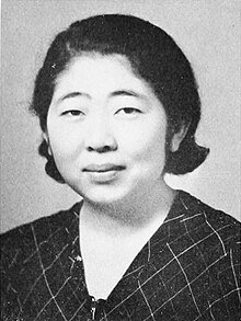 Portrait of an Asian woman in a black and white checked, v-neck blouse