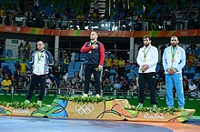 Quatre athlètes masculins se tiennent debout sur un podium olympique.