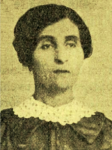 Sepia portrait photograph of a middle age woman with short dark hair wearing a white lace collar over a dark, collared blouse.