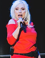 Debbie Harry looking to the right and holding a microphone