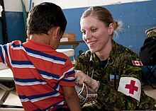 Uma enfermeira das Forças Canadenses cuidando de uma criança em El Salvador.