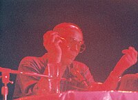 Фотография Томпсона в очках, говорящего в микрофон, но с красным светом.