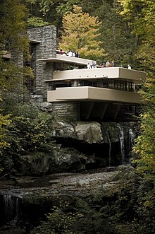 Una casa de estilo modernista que se encuentra ubicada en el bosque, con una terraza de varios niveles que cuelga sobre una cascada
