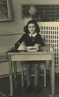אנה פרנק מצולמת בבית ספרה, ליד שולחן לימודיה.