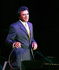 A man holding a microphone, dressed in a tuxedo.