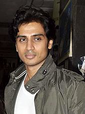 Shiv Panditt in a white T-shirt and camo jacket, looking away from the camera.