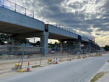 Long concrete viaduct viewed from street level with construction scaffolding