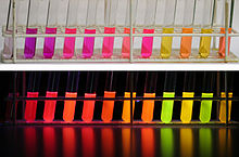 Colors of a single chemical (Nile red) in different solvents, under visible and UV light, showing how the chemical interacts dynamically with its solvent environment. Nile red 01.jpg