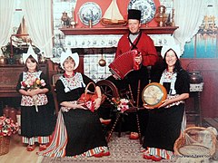 Família de turistas vestindo trajes típicos de Volendam, usando tamancos holandeses e segurando tulipas e queijos holandeses