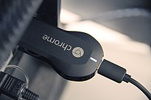 A first-generation Chromecast plugged into the HDMI port of a TV Chromecast plugged into TV.jpg