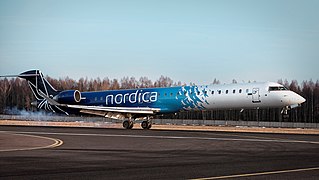 Inġenju tal-ajru Nordica (linja tal-ajru) li jinżel fl-Ajruport ta’ Tallinn/A Nordica (airline) aircraft landing at Tallinn Airport/Un avión de Nordica (aerolínea) aterrizando en el Aeropuerto de Tallin/Um pouso de avião da Nordica (companhia aérea) no aeroporto de Tallinn.