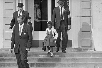 Ruby Bridges, premier enfant à bénéficier de l'abolition de la ségrégation scolaire aux États-Unis depuis les arrêts Brown v. Board of Education en 1954, escortée par des marshals en 1960. (définition réelle 3 000 × 1 996)