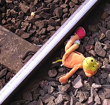 Photographie en gros plan d'une petite peluche posée à côté d'un rail.