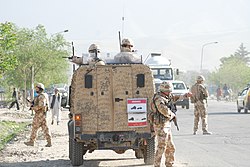 Armed soldiers in and around a military vehicle