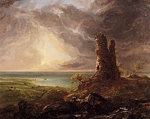 An oil painting showing a ruined stone tower on high ground in the foreground. In the rear is a coast. The sun shines through dark clouds in the sky above.