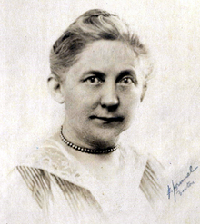 Middle-aged white woman wearing a necklace.